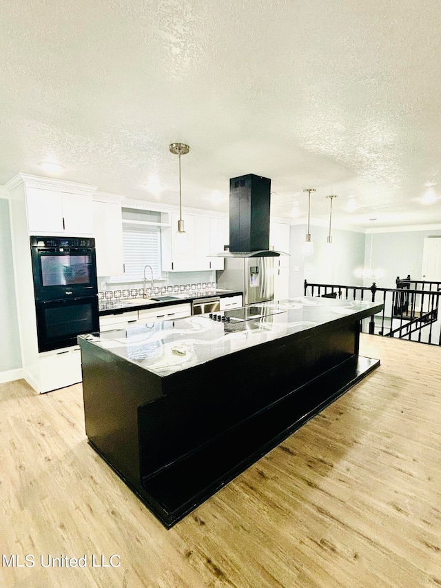 kitchen with range hood, light stone countertops, a kitchen island, and hanging light fixtures