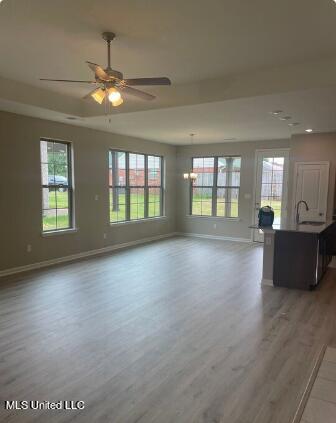 unfurnished living room featuring plenty of natural light, dark hardwood / wood-style floors, sink, and ceiling fan