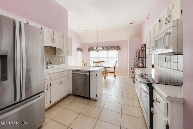 kitchen featuring a sink, light countertops, a peninsula, lofted ceiling, and stainless steel appliances