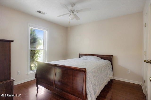 bedroom featuring baseboards, visible vents, multiple windows, and wood finished floors