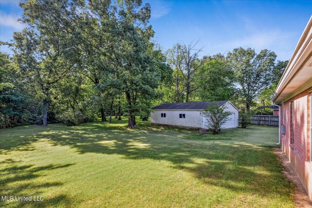 view of yard with fence, an outbuilding, and a garage