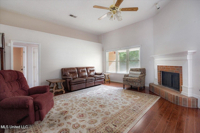 living area with ceiling fan, visible vents, wood finished floors, and a fireplace