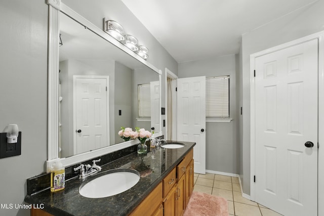 full bath featuring tile patterned floors, double vanity, baseboards, and a sink