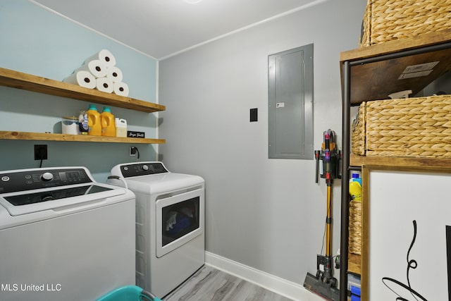 washroom with baseboards, electric panel, laundry area, light wood-style floors, and washer and dryer