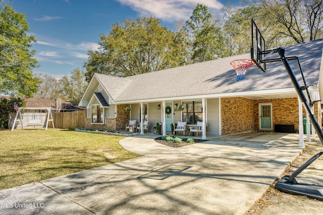 view of front facade with driveway, an attached carport, fence, a front yard, and brick siding