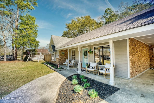 view of exterior entry with brick siding, a lawn, a porch, and a shingled roof