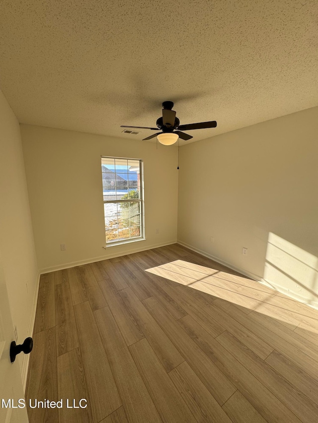 unfurnished room with ceiling fan, a textured ceiling, and light wood-type flooring