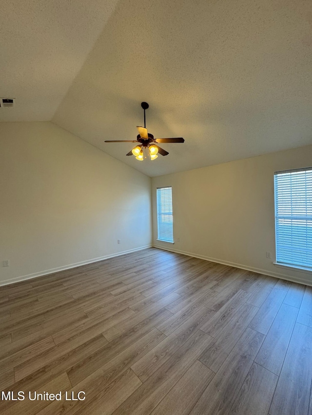 unfurnished room featuring a textured ceiling, ceiling fan, light hardwood / wood-style flooring, and vaulted ceiling