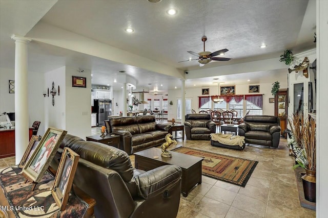 living room with light tile patterned floors, a textured ceiling, decorative columns, and ceiling fan