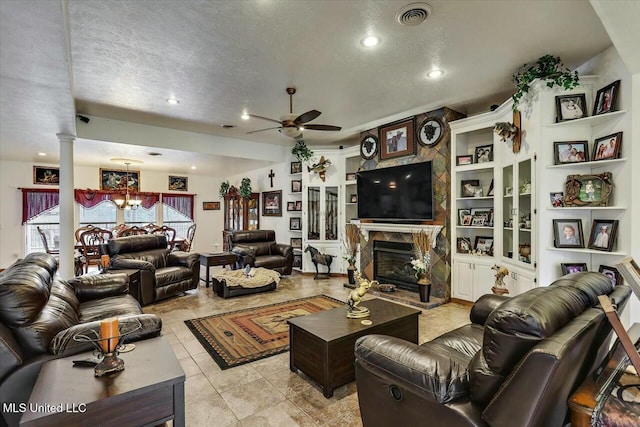 living room with ceiling fan with notable chandelier, decorative columns, light tile patterned floors, a high end fireplace, and a textured ceiling