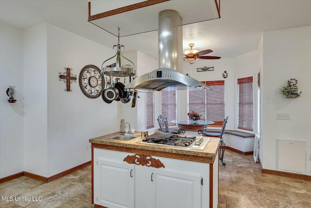 kitchen featuring sink, ceiling fan, stainless steel gas cooktop, white cabinets, and island exhaust hood