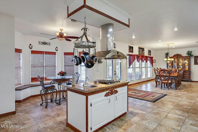 kitchen with sink, white cabinetry, an island with sink, island exhaust hood, and stainless steel gas stovetop