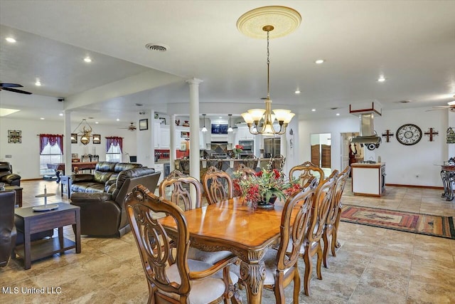 dining room with ornate columns and ceiling fan with notable chandelier