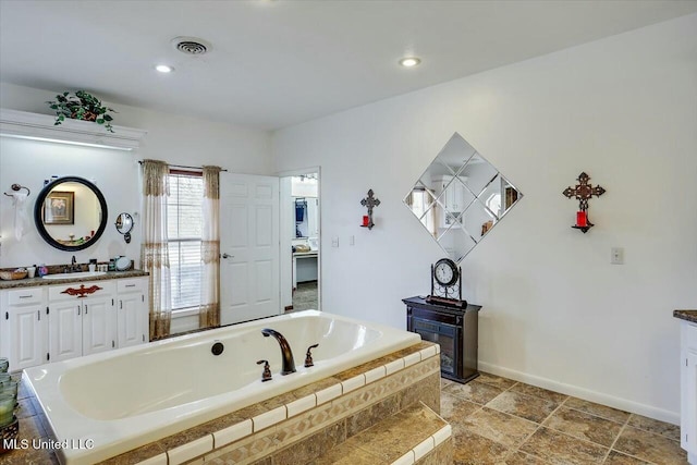 bathroom with tiled tub and vanity