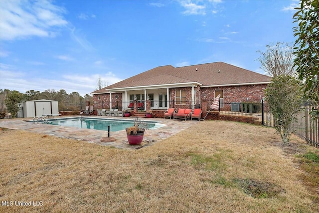 back of property featuring a fenced in pool, a patio, a lawn, and a shed