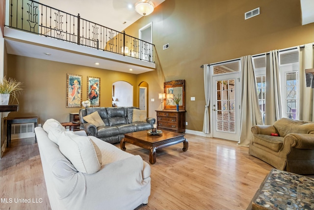 living room featuring a towering ceiling and light hardwood / wood-style floors