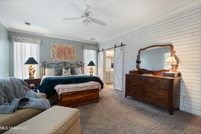 bedroom with crown molding, ceiling fan, ensuite bathroom, carpet, and a barn door