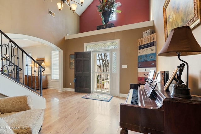 foyer featuring an inviting chandelier, high vaulted ceiling, and light wood-type flooring