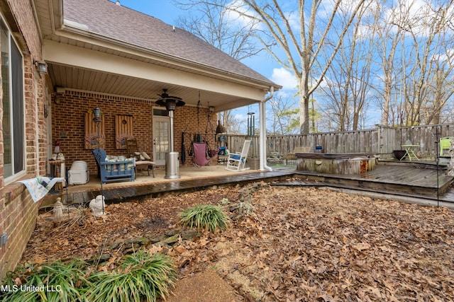 exterior space featuring a hot tub, a patio, a deck, and ceiling fan