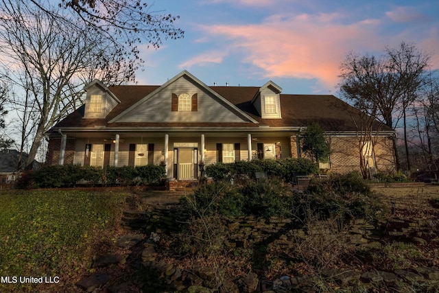 cape cod house featuring covered porch