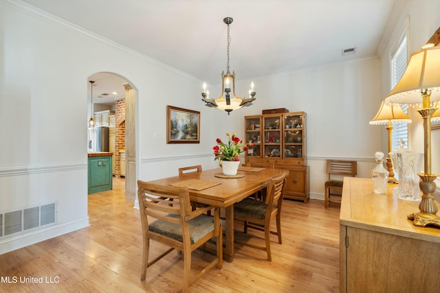 dining room with an inviting chandelier, crown molding, and light wood-type flooring