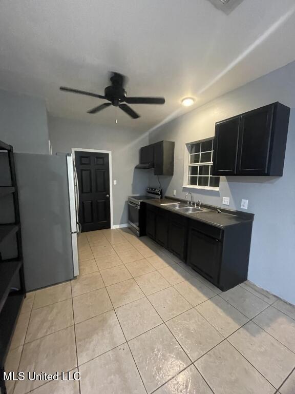 kitchen featuring electric range, sink, ceiling fan, stainless steel fridge, and light tile patterned flooring