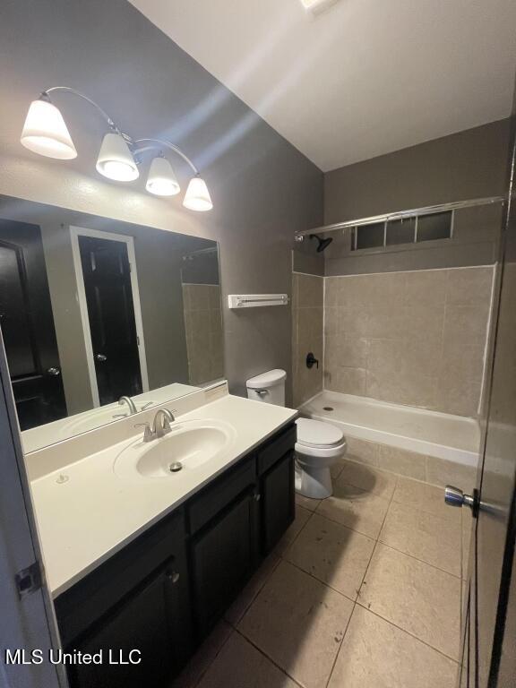 full bathroom featuring tile patterned flooring, tiled shower / bath combo, toilet, and vanity