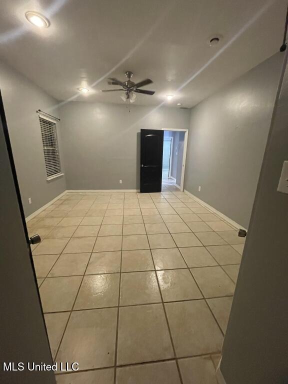 spare room with ceiling fan and light tile patterned flooring