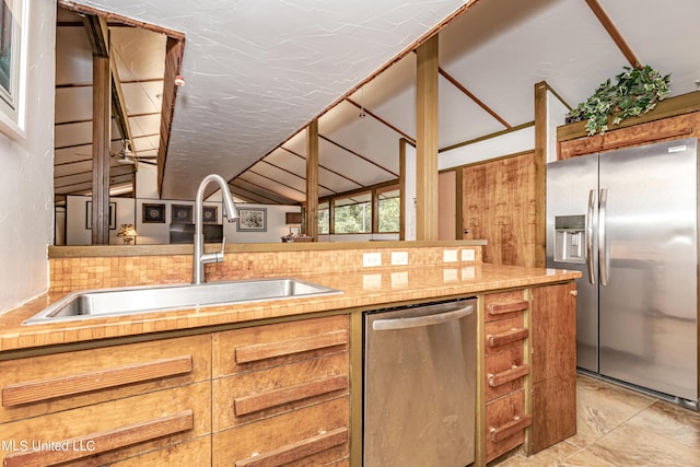 kitchen with lofted ceiling, tasteful backsplash, light tile patterned floors, sink, and stainless steel appliances