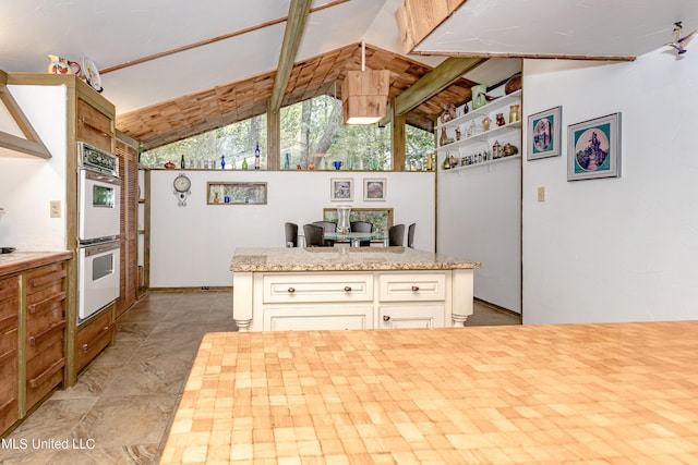 kitchen with lofted ceiling, light stone countertops, and white double oven