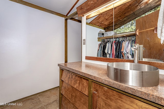 interior space featuring vaulted ceiling with beams and sink