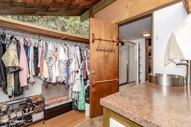 spacious closet with lofted ceiling, sink, and light wood-type flooring