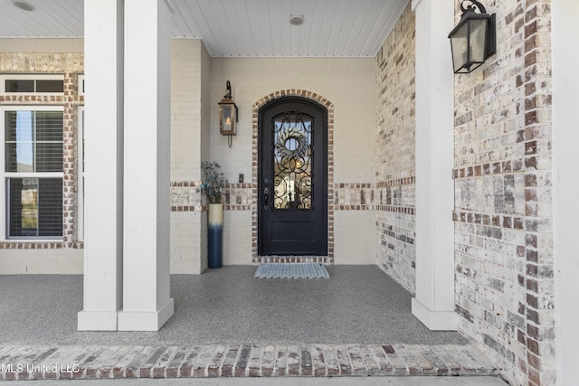 entrance to property with brick siding and a porch