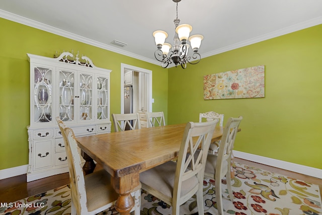 dining space with ornamental molding, an inviting chandelier, and hardwood / wood-style floors