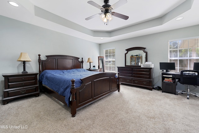 bedroom featuring light carpet, ceiling fan, and a raised ceiling