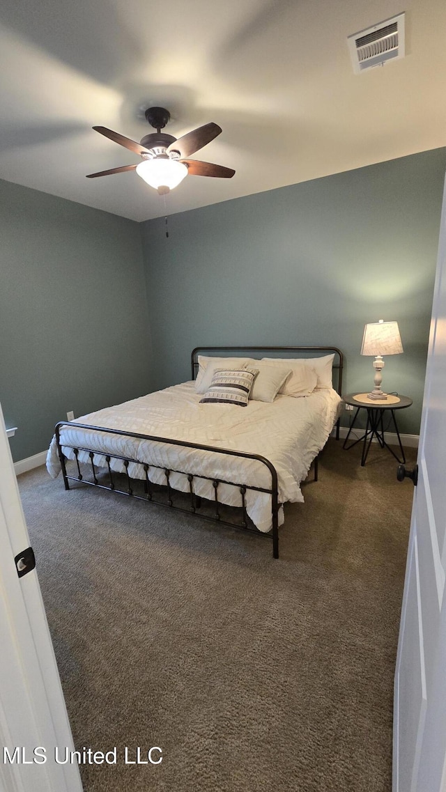 bedroom with a ceiling fan, dark colored carpet, visible vents, and baseboards