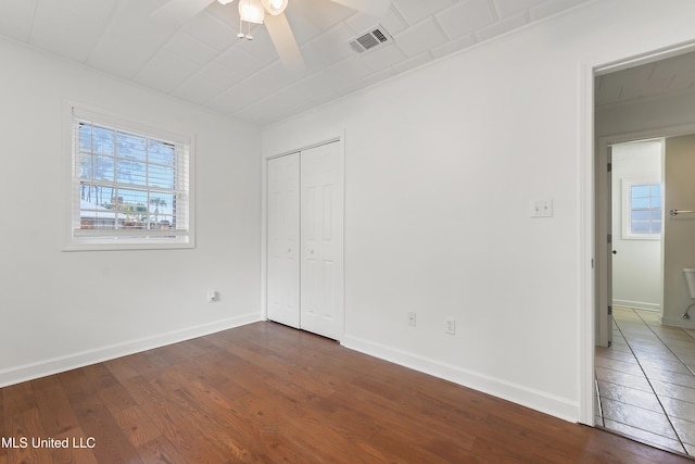 unfurnished bedroom featuring ceiling fan, dark wood-type flooring, and a closet