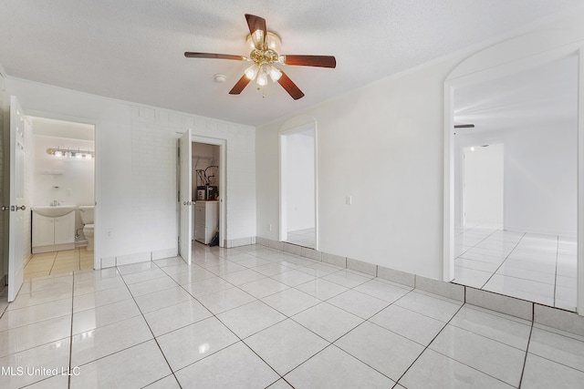 empty room with a textured ceiling, ceiling fan, light tile patterned floors, and washer / clothes dryer