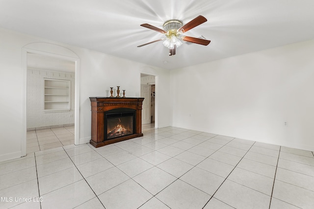 tiled living room with ceiling fan and built in shelves