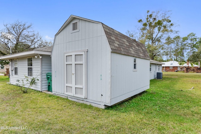 view of outdoor structure featuring central AC and a yard