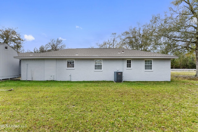 rear view of house featuring central AC unit and a yard