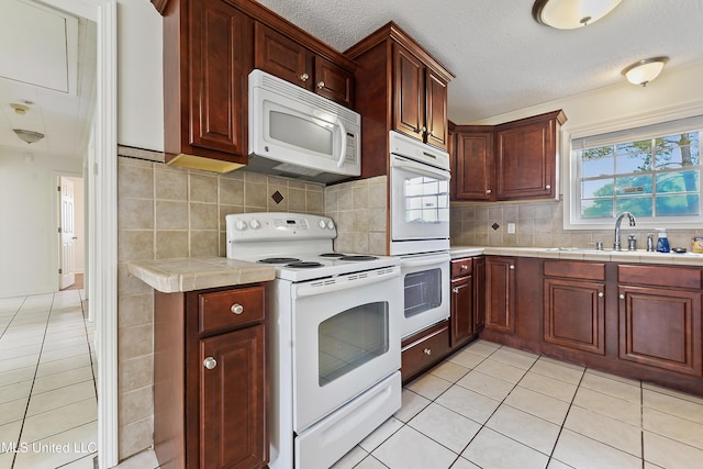 kitchen with backsplash, white appliances, light tile patterned flooring, a textured ceiling, and sink