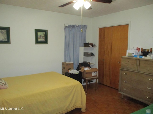 bedroom featuring dark parquet flooring, a closet, and ceiling fan