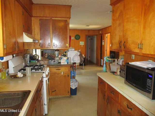 kitchen with white gas stove and wood walls