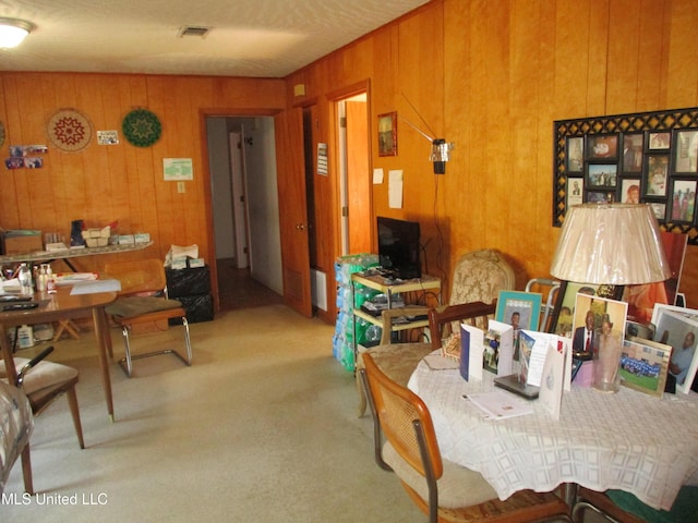 carpeted dining area with wood walls