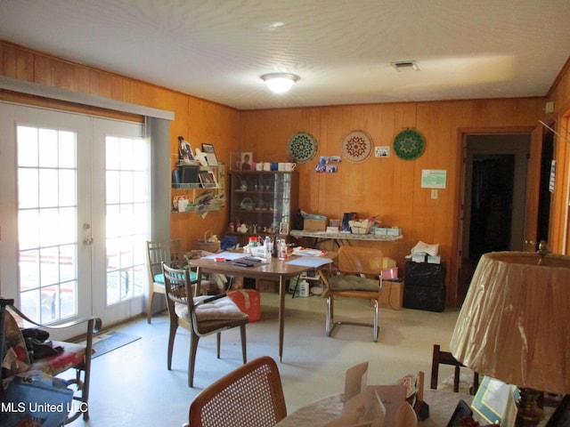 dining room with wood walls, a healthy amount of sunlight, and french doors