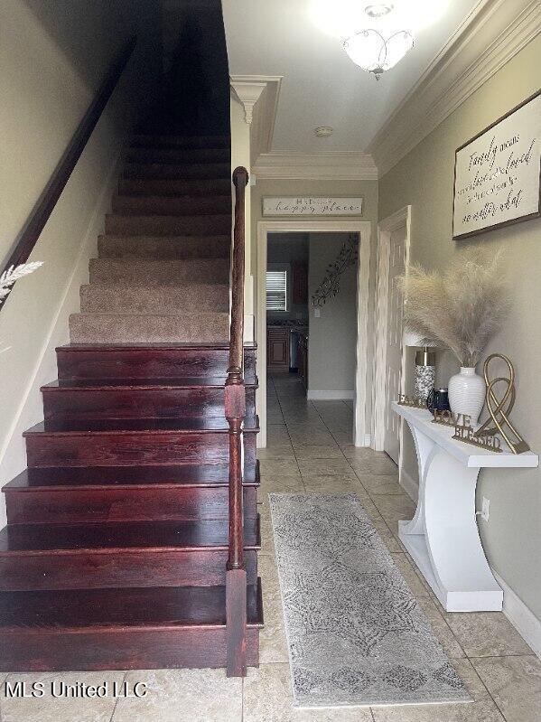 staircase featuring ornamental molding and tile patterned floors