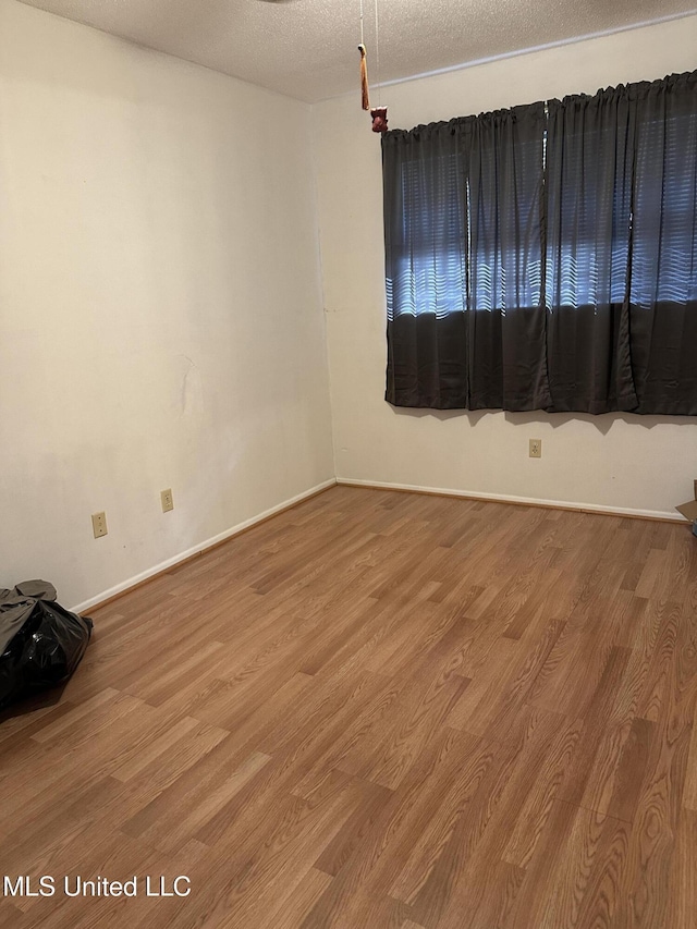 empty room with wood-type flooring and a textured ceiling