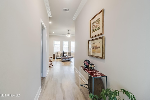 corridor with light wood finished floors, recessed lighting, visible vents, ornamental molding, and baseboards