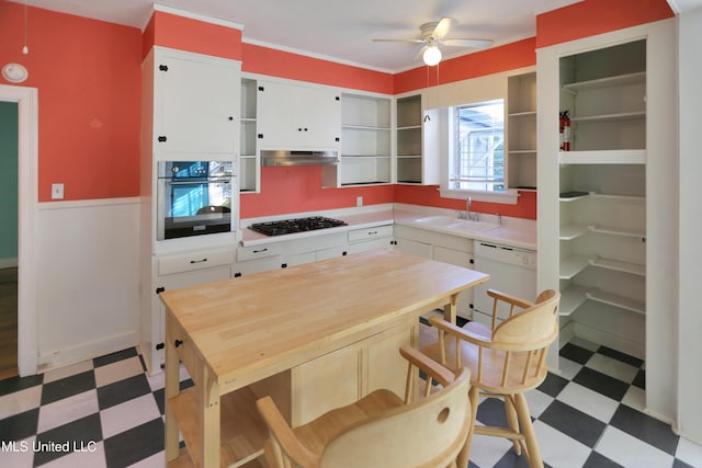 kitchen with stainless steel oven, white dishwasher, sink, range hood, and white cabinetry